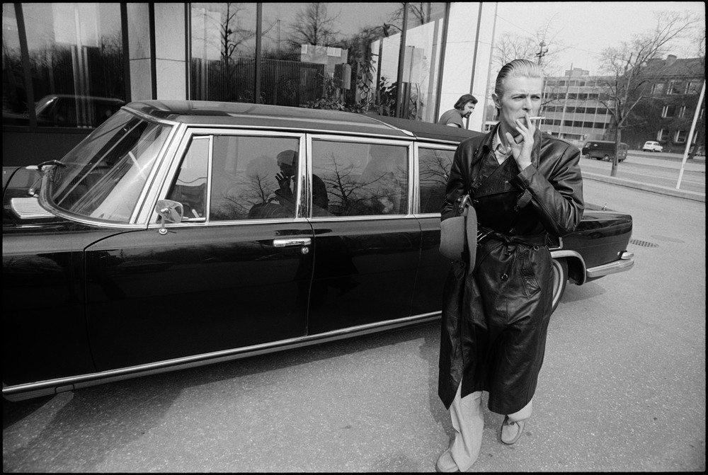 David Bowie smokes a cigarette next to his limousine in 1976