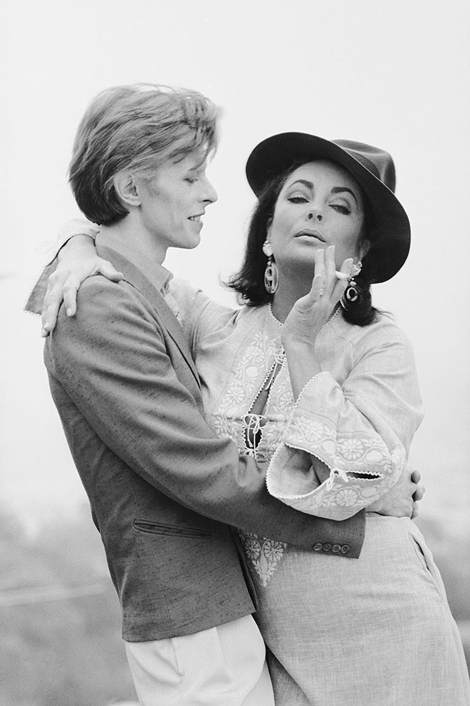 Singer David Bowie shares a cigarette with actress Elizabeth Taylor in Beverly Hills, 1975. It was the first occasion that the pair had met.